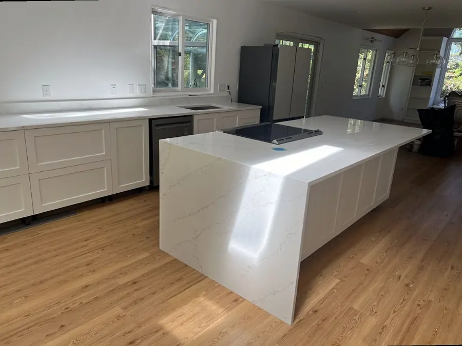 Waterfall quartz kitchen island with a black cooktop